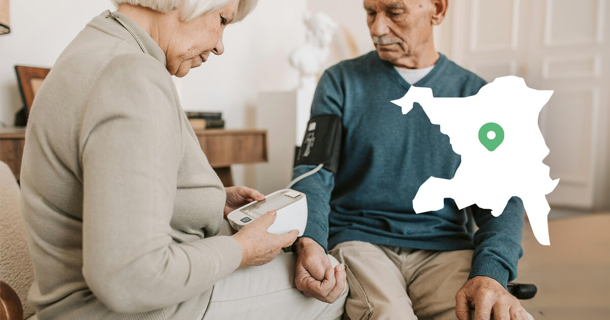 An elderly man is helped to measure his blood pressure at home