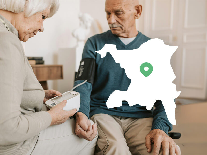 An elderly man is helped to measure his blood pressure at home