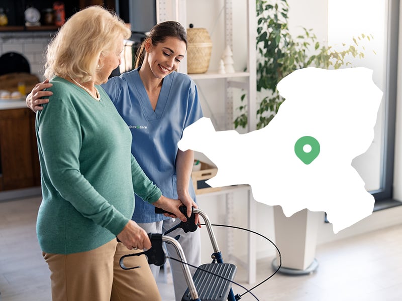 An elderly woman is helped to walk by a nurse