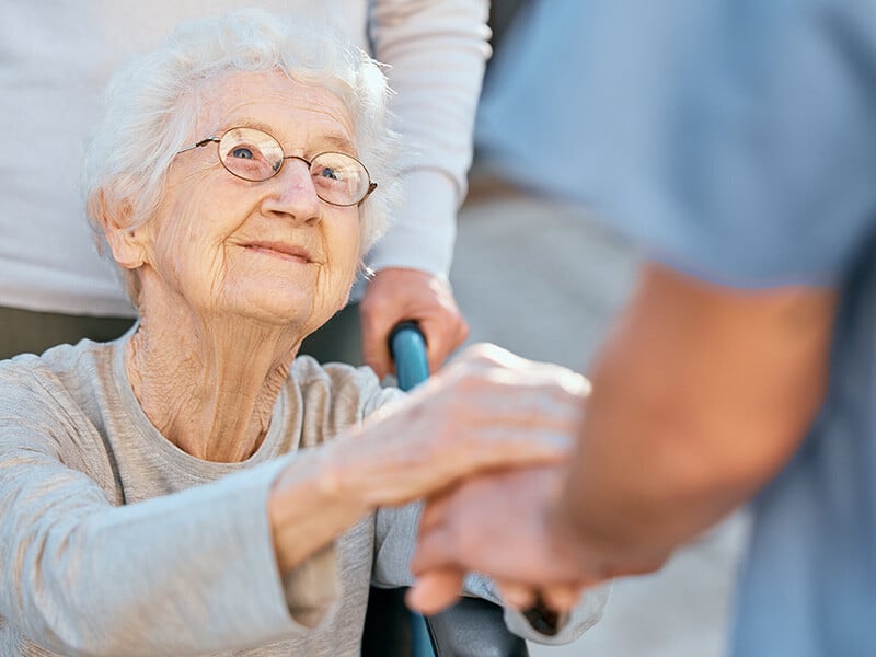 Old woman in wheelchair looks up at caregiver and smiles; shows a reason for returning to caregiving