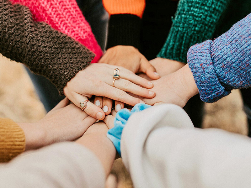 A group of people with their hands placed on top of each other, symbolizing team spirit and cohesion.