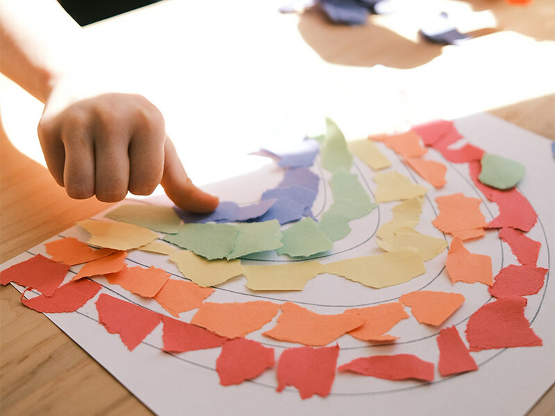 Child doing handicrafts with colorful pieces of paper, concept for creative childcare.