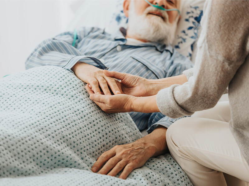 Caring hand gently holds the hand of an elderly patient in bed, caring palliative care, focus on the hands that provide comfort.