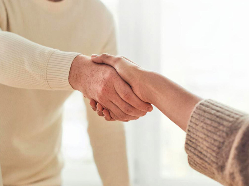 Two people shaking hands. The handshakes are firm and seem to express trust and respect. The background is blurred.