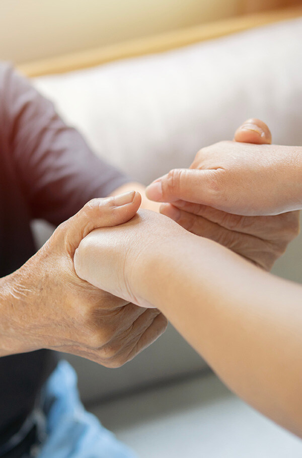 Close-up of the hands of a private Spitex nurse lovingly holding the hand of an elderly person.