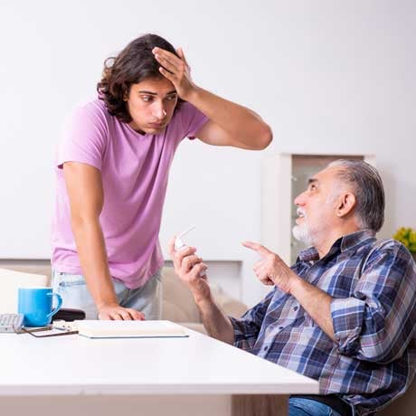 An old and a young man speak. The old man explains something, the young man holds his head and looks stressed.